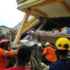 Lực lượng cứu hộ tìm kiếm nạn nhân dưới đống đổ nát của tòa nhà bị sập sau trận động đất tại đảo Sulawesi, miền Trung Indonesia ngày 15/1/2021. (Ảnh: AFP/TTXVN)