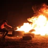 Người biểu tình Palestine đốt cháy lốp xe trong cuộc đụng độ với binh sỹ Israel tại Dải Gaza, ngày 28/8. (Ảnh: THX/TTXVN)