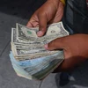 Người dân kiểm đếm đồng USD và tiền bolivar Venezuela trên đường phố Caracas (Venezuela). (Ảnh: AFP/TTXVN)
