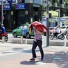Một người dân tại Thành phố Hồ Chí Minh dùng áo che kín đầu, bước vội giữa trời nắng nóng. (Ảnh: Hồng Giang/TTXVN)