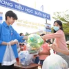 Đoàn viên Thanh niên xã Suối Đá thu gom chai nhựa sử dụng một lần và phát phiếu tham gia phiên chợ chai cho người dân. (Ảnh: Minh Phú/TTXVN)