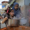 Trẻ em Palestine nhận thức ăn cứu trợ tại thành phố Rafah, Dải Gaza. (Ảnh: THX/TTXVN)