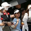 Người dân di chuyển trên đường phố dưới trời nắng nóng tại Bắc Kinh, Trung Quốc. (Ảnh: AFP/TTXVN)