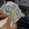 Người dân rút tiền đô la Singapore từ máy rút tiền tự động (ATM) tại Singapore. (Ảnh: AFP/TTXVN)