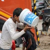 Người dân vội vàng uống nước ngay sau khi hứng được từ xe bồn của chính phủ. (Ảnh: Ngọc Thúy/TTXVN)