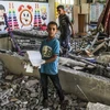 Trẻ em bên đống đổ nát của trường học bị trúng không kích của Israel tại thành phố Gaza ngày 25/6. (Ảnh: THX/TTXVN)