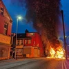Vụ bạo loạn khiến một xe buýt bốc cháy và một xe cảnh sát bị lật. (Ảnh: The Guardian)