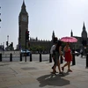 Người dân di chuyển dưới trời nắng nóng tại London, Anh. (Ảnh: AFP/TTXVN)