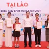 Đại biện lâm thời Đại sứ quán Việt Nam tại Lào Phan Minh Chiến trao phần thưởng cho các thí sinh đạt giải Lễ Tôn vinh tiếng Việt tại Lào năm 2024. (Ảnh: Xuân Tú/TTXVN)