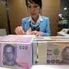 Nhân viên ngân hàng kiểm đếm đồng baht tại Bangkok, Thái Lan. (Ảnh: AFP/TTXVN)