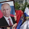 Một phụ nữ trẻ người Chechen đang cầm chân dung của Tổng thống Nga Vladimir Putin. Cô quàng quốc kỳ Nga lên đầu trong buổi diễu hành để kỷ niệm Ngày nước Nga ở vùng Grozny. (Nguồn: Sputniknews)