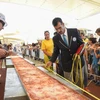 Nhân viên của Sách kỷ lục Guinness đo chiều dài chiếc bánh pizza tại Hội chợ triển lãm EXPO ở Milan. (Nguồn: AFP/TTXVN) 