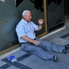 Một người dân Hy Lạp ngồi bên ngoài chi nhánh ngân hàng ở Thessaloniki chờ rút tiền. (Nguồn: AFP/TTXVN) 