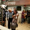 Binh sỹ Israel sơ tán người dân tại một siêu thị bên trong bến xe buýt trung tâm thành phố Jerusalem, sau khi cụ bà bị tấn công, ngày 14/10. (Nguồn: Reuters/TTXVN) 