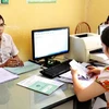 Nhân viên Bảo hiểm Xã hội huyện Phù Cừ thực hiện giao dịch thẻ bảo hiểm y tế với các đại lý xã, phường. (Ảnh: Dương Ngọc/TTXVN) 