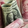 Tiền giấy mệnh giá 100 nhân dân tệ của Trung Quốc và đồng đôla Mỹ (giữa). (Nguồn: AFP/ TTXVN)