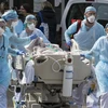Nhân viên y tế chuyển bệnh nhân nhiễm COVID-19 tới bệnh viện (Nguồn:AFP/TTXVN)
