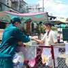 Phát thực phẩm, nhu yếu phẩm cho người dân trong khu vực bị phong tỏa tại con hẻm trên đường Đoàn Phú Tứ, phường An Lạc A, TP.Hồ Chí Minh. (Ảnh: TTXVN phát)