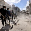 Các tình nguyện viên dọn dẹp đống đổ nát của các tòa nhà bị sập sau loạt không kích của Israel tại Dải Gaza, ngày 23/5. (Ảnh: AFP/TTXVN) 
