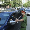 Lực lượng chức năng kiểm tra giấy tờ tuỳ thân và xác nhận đi làm, ra ngoài của cơ quan với người dân lưu thông trên đường Đào Tấn, Hà Nội (sáng 28/7/2021). (Ảnh: Lâm Khánh/TTXVN)