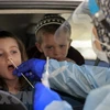 Nhân viên y tế lấy mẫu xét nghiệm COVID-19 cho một em nhỏ tại Berlin. (Ảnh: AFP/TTXVN)