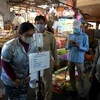 Người dân kiểm tra thân nhiệt trước khi vào chợ để phòng chống dịch COVID-19 tại Lào. (Ảnh: AFP/TTXVN)