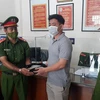 Đại úy Nguyễn Đức Dũng trả lại số tiền cho người bỏ quên. (Ảnh: TTXVN phát)