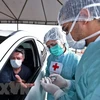 Nhân viên y tế xét nghiệm nhanh COVID-19 cho người dân tại một bãi đỗ xe ở Brasilia, Brazil. (Nguồn: AFP/TTXVN)