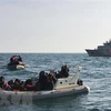 Lực lượng cứu hộ (phía trước) chặn tàu chở người di cư từ Pháp băng qua eo biển Manche. (Ảnh: AFP/TTXVN)