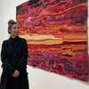 Nghệ sỹ trẻ Tia-Thủy Nguyễn với một trong những tác phẩm trong bộ sưu tập "Lấp lánh giữa bao la." (Ảnh: Nguyễn Thu Hà/TTXVN) 