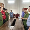 Cơ quan Cảnh sát điều tra, Công an tỉnh Sơn La tổ chức thi hành các quyết định tố tụng đối với Lò Minh Phương (áo đỏ). (Ảnh: TTXVN phát)