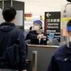 Nhân viên hướng dẫn hành khách tại khu vực kiểm dịch của sân bay Narita (Nhật Bản). (Ảnh: AFP/TTXVN)