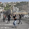 Người biểu tình Palestine ném đá về phía cảnh sát Israel trong cuộc đụng độ tại khu vực Đền Al-Aqsa ở Đông Jerusalem ngày 15/4/2022. (Ảnh: AFP/TTXVN)