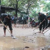 Lực lượng cảnh sát cơ động giúp người dân Ghềnh Ráng, Quy Nhơn (Bình Định) dọn bùn đất trên đường. (Ảnh: Sỹ Thắng/TTXVN)