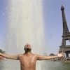 Người dân giải nhiệt tránh nắng nóng tại một đài phun nước ở Paris (Pháp), ngày 18/6/2022. (Ảnh: AFP/TTXVN)