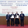 Chủ tịch Hội Hữu nghị Việt Nam-Lào Trần Văn Túy và Đại sứ Đặc mệnh toàn quyền nước Cộng hòa Dân chủ Nhân dân Lào tại Việt Nam Sengphet Houngboungnuang trao giải Nhất cho các tác giả. (Ảnh: An Đăng/TTXVN)