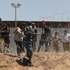 Người di cư vượt qua hàng rào biên giới Mỹ-Mexico ở Texas (Mỹ), ngày 8/5/2023. (Ảnh: AFP/TTXVN)