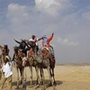 Khách du lịch cưỡi lạc đà khi tham quan quần thể Kim tự tháp Giza ở ngoại ô Cairo (Ai Cập). (Ảnh: AFP/TTXVN)