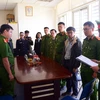 Cơ quan Điều tra đọc lệnh bắt Ngô Văn Thành (thường phục, phải) - Trưởng phòng Trung tâm Khuyến công và Tư vấn Phát triển Công nghiệp. (Ảnh: TTXVN phát)