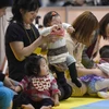 Cha mẹ cùng các em bé tham gia một cuộc thi ở Tokyo (Nhật Bản). (Ảnh: AFP/TTXVN)