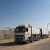 Xe tải chở hàng viện trợ qua cửa khẩu Kerem Shalom vào Dải Gaza ngày 15/4/2024. (Ảnh: AFP/TTXVN)