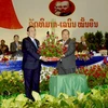 Tổng Bí thư Đảng Nhân dân cách mạng Lào khóa IX Choummaly Sayasone (trái) tặng hoa chúc mừng Tổng Bí thư khóa X Bounnhang Vorachith (phải). (Ảnh: Phạm Kiên/Vietnam+)