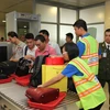 Thanh niên tình nguyện giúp đỡ hành khách tại khu vực máy soi kiểm tra an ninh ở sân bay Tân Sơn Nhất. (Ảnh: Mạnh Linh/TTXVN)