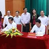 Bộ trưởng Bộ Tài chính Đinh Tiến Dũng (bên trái) và Tổng giám đốc TTXVN Nguyễn Đức Lợi ký văn kiện phối hợp tuyên truyền. (Ảnh: Hoàng Hùng/TTXVN)