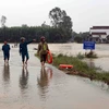 Lực lượng công an xã Hành Minh, huyện Nghĩa Hành túc trực kiểm tra các đường giao thông bị ngập lũ không cho người dân tự ý lưu thông. (Ảnh: Trần Lê Lâm/TTXVN)