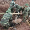 Lực lượng công binh tiến hành trục vớt quả bom nằm sâu dưới lòng đất. (Ảnh: Mai Ngoan/TTXVN)