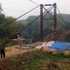 Công nhân Công ty trách nhiệm hữu hạn Thành Long đang khẩn trương sửa chữa cầu treo Bình Yên. (Ảnh Quang Đán/TTXVN)