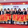 Tổng Giám đốc TTXVN Nguyễn Đức Lợi trao cờ thi đua của ngành cho các tập thể có nhiều thành tích xuất sắc trong phong trào thi đua năm 2016. (Ảnh: Thành Đạt/TTXVN)