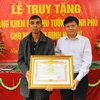 Phó Tổng Giám đốc Thông tấn xã Việt Nam Đinh Đăng Quang thừa ủy quyền của Thủ tướng Chính phủ trao Bằng khen của Thủ tướng Chính phủ cho gia đình cố Nhà báo Đinh Hữu Dư. (Ảnh: Minh Đức/TTXVN)