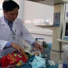 Bác sỹ Lò Văn Nhay kiểm tra sức khỏe của bệnh nhi Cà Văn Thắng tại phòng hồ sức sau mổ. (Ảnh: Diệp Anh/TTXVN)